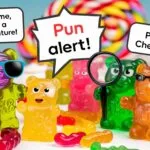 Several gummy bear candies are arranged on a white surface, with colorful blurred candy in the background. One purple gummy bear wears blue sunglasses